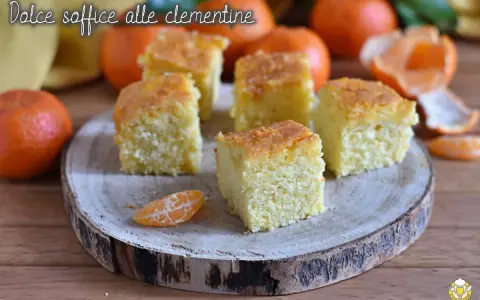 Fette di torta di clementine soffice, guarnite con scorza d'arancia, su un tagliere di legno.