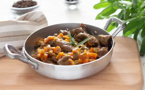 Cinghiale in umido fatto in casa da Benedetta, un piatto succulento con carne tenera e verdure, guarnito con rosmarino e salvia.