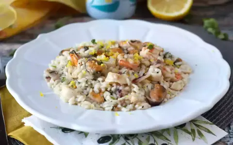 Un invitante risotto allo scoglio, ricco di cozze, gamberi e calamari, guarnito con scorza di limone.