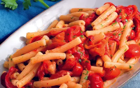Un piatto invitante di pasta con i peperoni alla pugliese, condita con pomodoro fresco e prezzemolo.