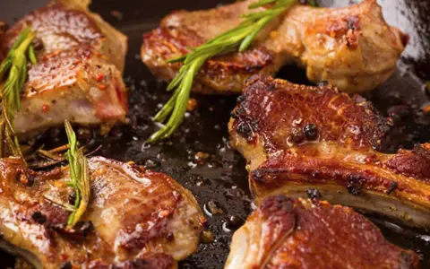 Succulento agnello in padella, dorato e profumato con rosmarino e pepe.