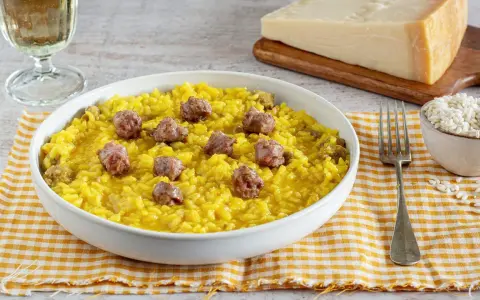 Un invitante risotto alla monzese, giallo intenso e ricco di saporiti pezzi di salsiccia, pronto per essere gustato.