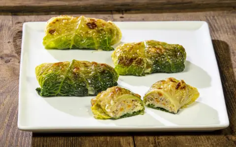 Cinque capunet piemontesi, involtini di verza ripieni, serviti su un piatto bianco.