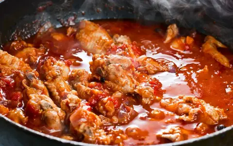 Succulenta carne alla pizzaiola che sobbolle in padella, sprigionando un invitante vapore. Pezzi di carne tenera immersi in un ricco sugo di pomodoro.