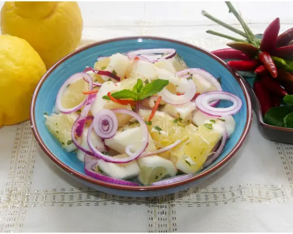 Fresca insalata di limoni, pompelmo, cipolla rossa e peperoncino, guarnita con menta.