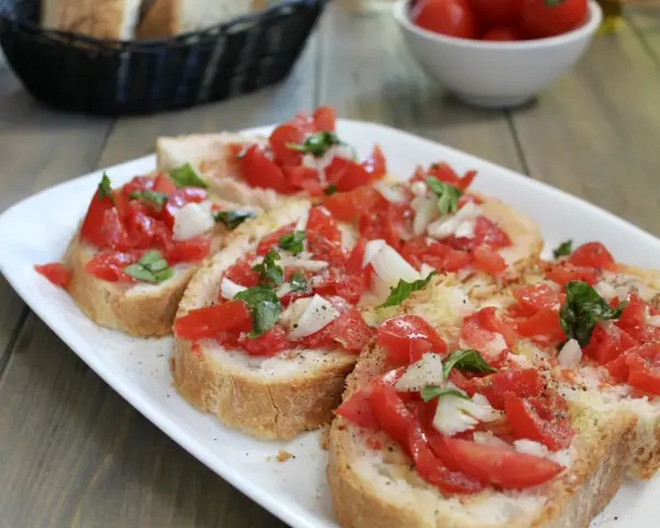 Fette di pane tostato condite con pomodoro fresco, cipolla e basilico, un classico della panzanella romana.