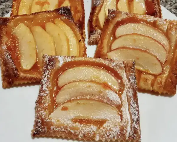 Deliziose sfogliatine di mele, dorate e lucide, cosparse di zucchero a velo. Un dolce invitante e profumato.