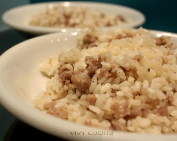 Risotto alla mantovana ingredienti: riso cremoso con salsiccia sbriciolata, servito in una ciotola bianca.