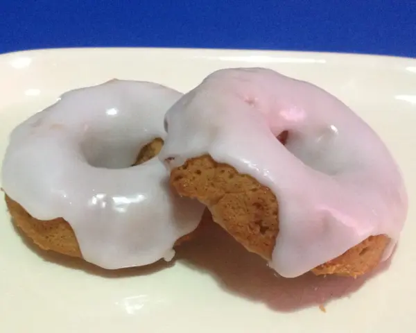 Due ciambelle con glassa di zucchero bianca e lucida, perfette per chi vuole imparare come fare la glassa di zucchero.