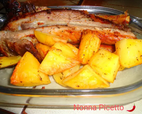 Costine di maiale al forno con patate dorate, un piatto succulento e saporito, pronto per essere gustato.