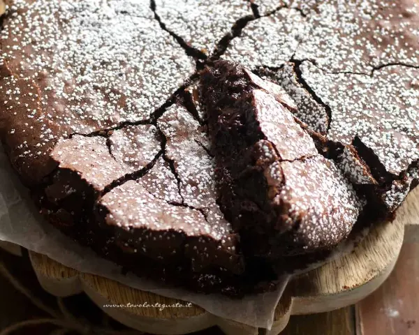 Torta fondente al cioccolato, con una crosta screpolata e cosparsa di zucchero a velo, pronta per essere gustata.