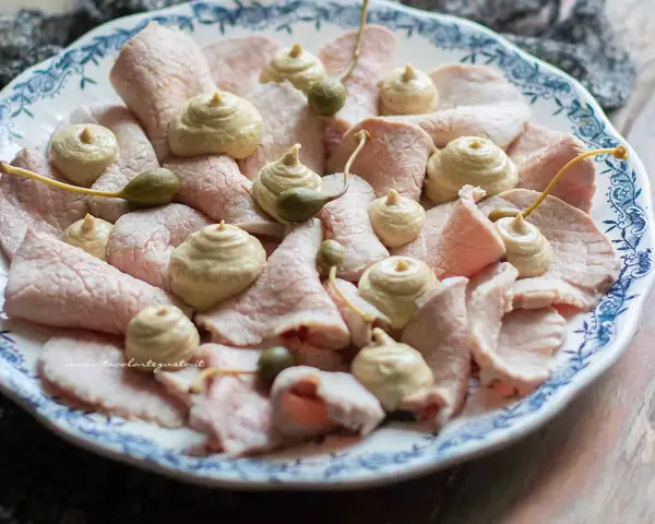 Vitello tonnato ricetta originale piemontese: fettine sottili di vitello rosa, guarnite con salsa tonnata e capperi.