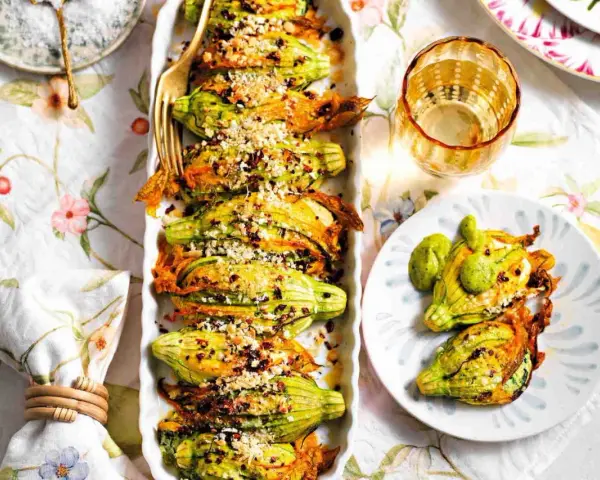 Deliziosi fiori di zucca ripieni, dorati e croccanti, serviti su un piatto con un tocco di verde.