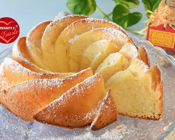 Un soffice ciambellone allo yogurt greco, spolverato di zucchero a velo, pronto per essere gustato.