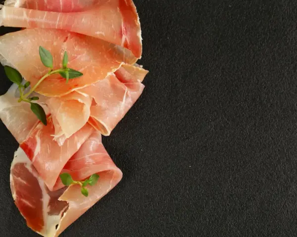 Fettine di prosciutto crudo e speck, con rametti di timo, per mostrare la differenza tra speck e prosciutto crudo.
