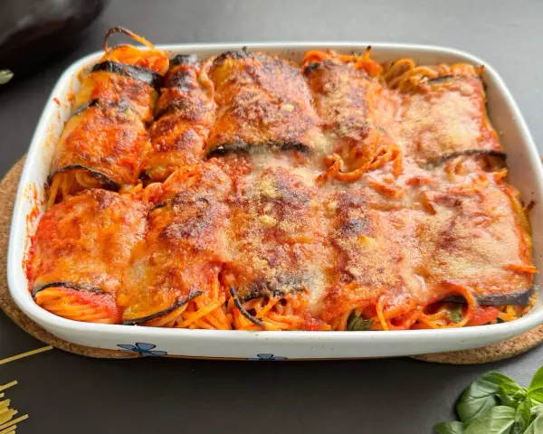 Involtini di melanzane ripieni di spaghetti al sugo, gratinati al forno con formaggio fuso.