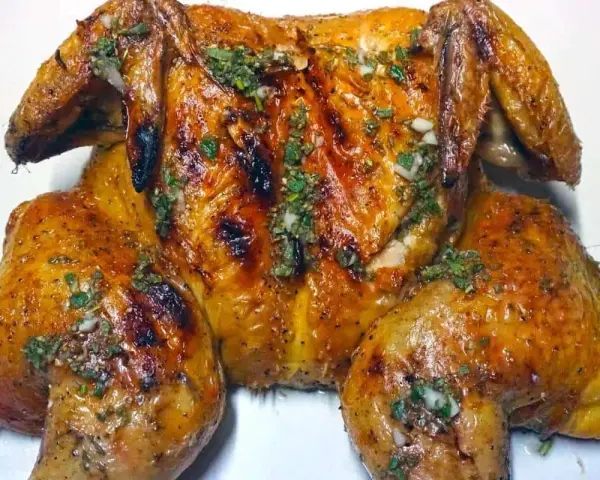 Un succulento pollo alla brace, dorato e profumato, condito con erbe aromatiche e aglio.