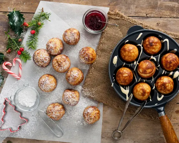 Frittelle dolci in padella, spolverate di zucchero a velo, pronte per essere gustate con marmellata.