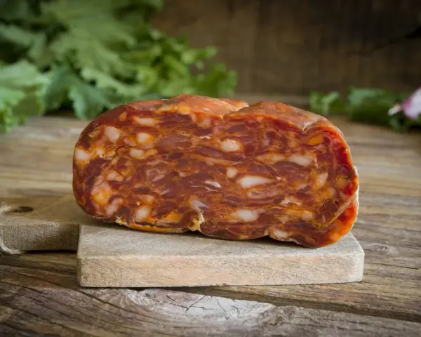 Un pezzo di salame stagionato su tagliere di legno. La differenza tra salame e sopressa è nella grana: qui si vede la carne tritata grossolanamente.
