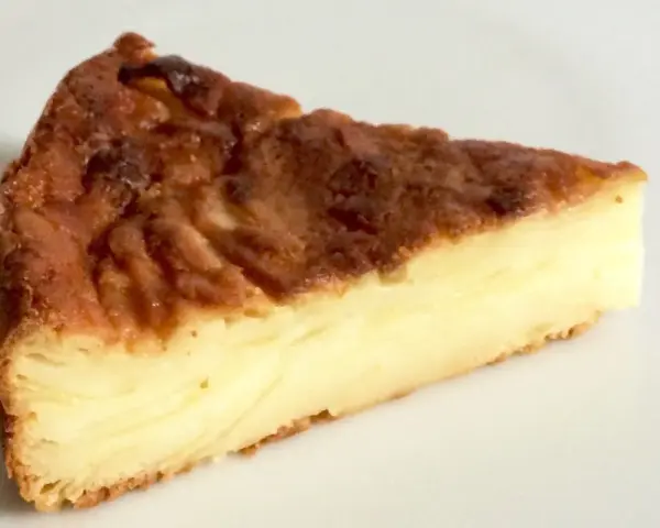 Una fetta di torta di mele fondente, con strati dorati e un ripieno cremoso.
