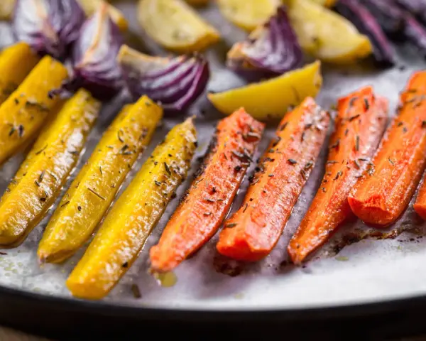 Carote, cipolle rosse e patate dorate, un tripudio di verdure al forno, condite con erbe aromatiche e olio.