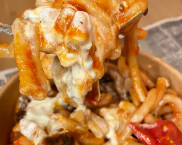 Primo piatto cremoso di pasta alla checca, con pomodoro e mozzarella filante, servito in un contenitore da asporto.