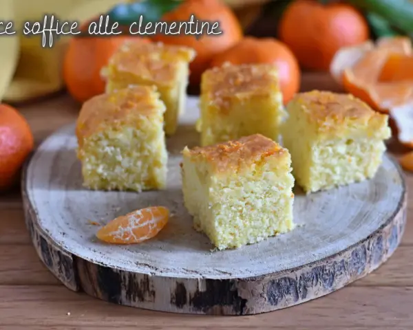 Fette di torta di clementine soffice, guarnite con scorza d'arancia, su un tagliere di legno.