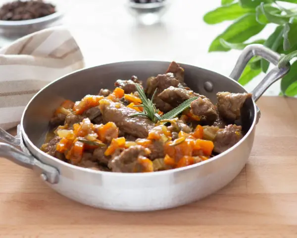 Cinghiale in umido fatto in casa da Benedetta, un piatto succulento con carne tenera e verdure, guarnito con rosmarino e salvia.