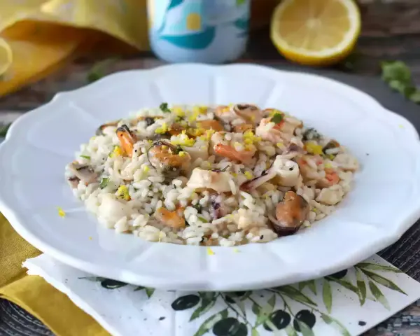 Un invitante risotto allo scoglio, ricco di cozze, gamberi e calamari, guarnito con scorza di limone.
