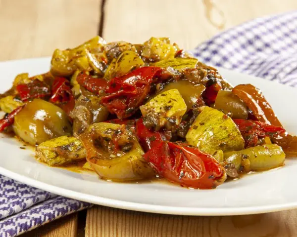 Un piatto invitante di verdure miste cotte, un'ottima gurguglione ricetta, con peperoni, zucchine e pomodori conditi con erbe aromatiche.