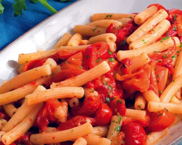 Un piatto invitante di pasta con i peperoni alla pugliese, condita con pomodoro fresco e prezzemolo.