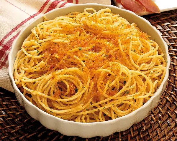 Spaghetti alla bottarga, un piatto saporito con pasta dorata e una generosa spolverata di uova di pesce essiccate.
