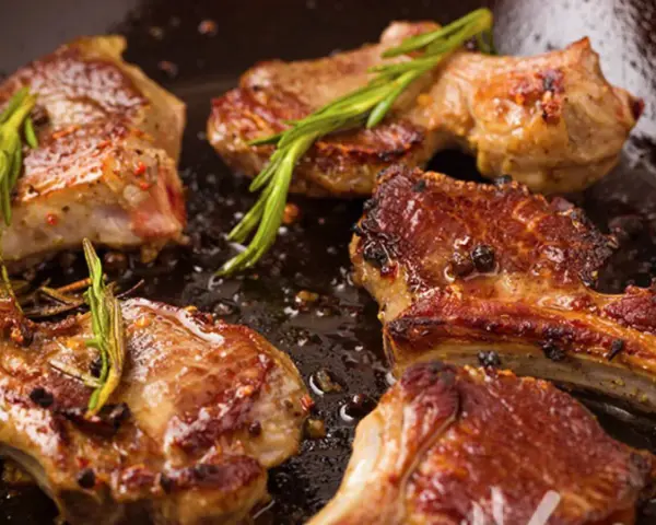 Succulento agnello in padella, dorato e profumato con rosmarino e pepe.