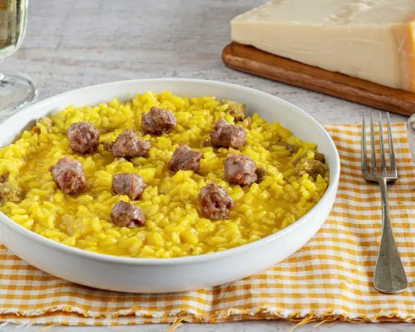 Un invitante risotto alla monzese, giallo intenso e ricco di saporiti pezzi di salsiccia, pronto per essere gustato.