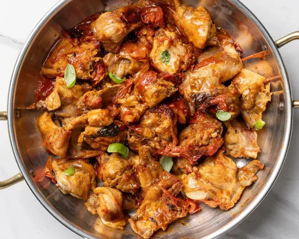 Un saporito coniglio all'ischitana, cotto in padella con pomodoro e basilico, pronto per essere gustato.