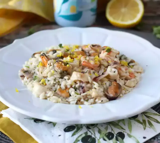 Un invitante risotto allo scoglio, ricco di cozze, gamberi e calamari, guarnito con scorza di limone.