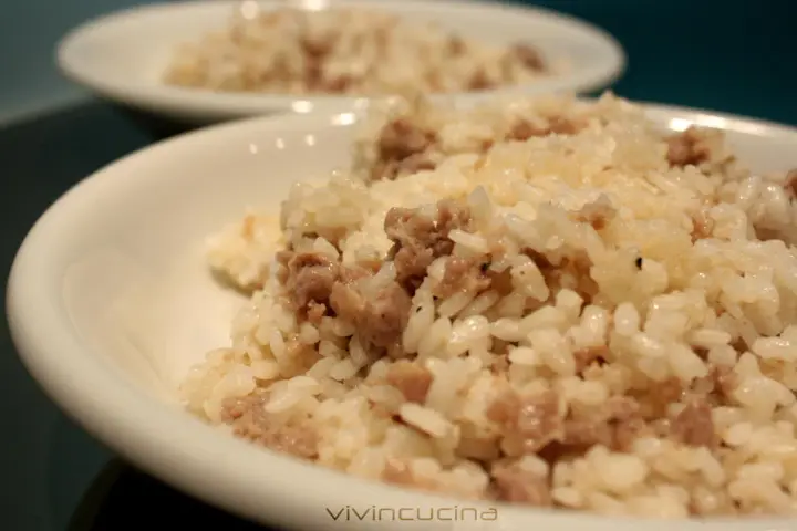Risotto alla mantovana ingredienti: riso cremoso con salsiccia sbriciolata, servito in una ciotola bianca.