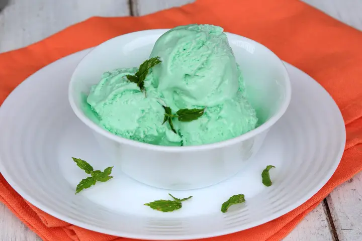 Coppa di cremoso gelato alla menta con latte condensato, guarnito con foglie di menta fresca.