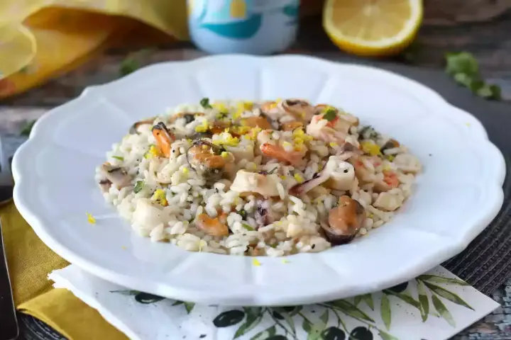 Un invitante risotto allo scoglio, ricco di cozze, gamberi e calamari, guarnito con scorza di limone.