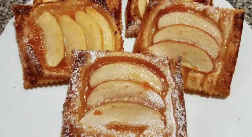 Deliziose sfogliatine di mele, dorate e lucide, cosparse di zucchero a velo. Un dolce invitante e profumato.