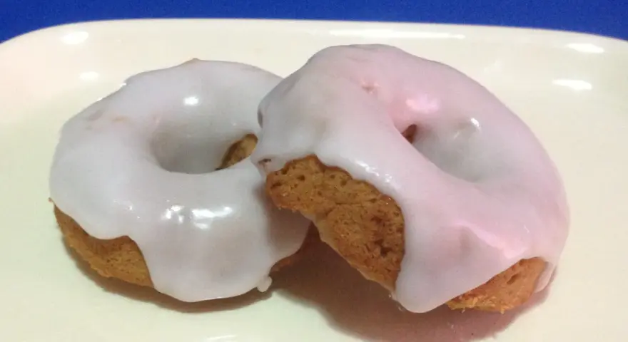 Due ciambelle con glassa di zucchero bianca e lucida, perfette per chi vuole imparare come fare la glassa di zucchero.