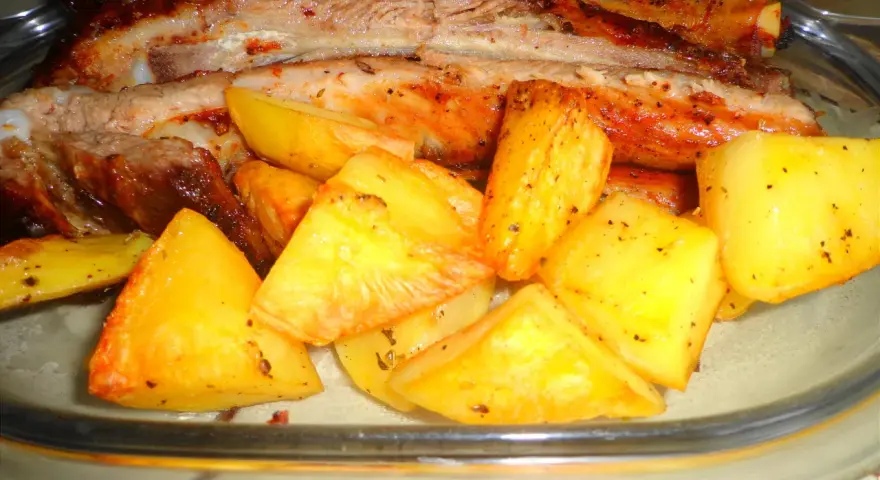 Costine di maiale al forno con patate dorate, un piatto succulento e saporito, pronto per essere gustato.