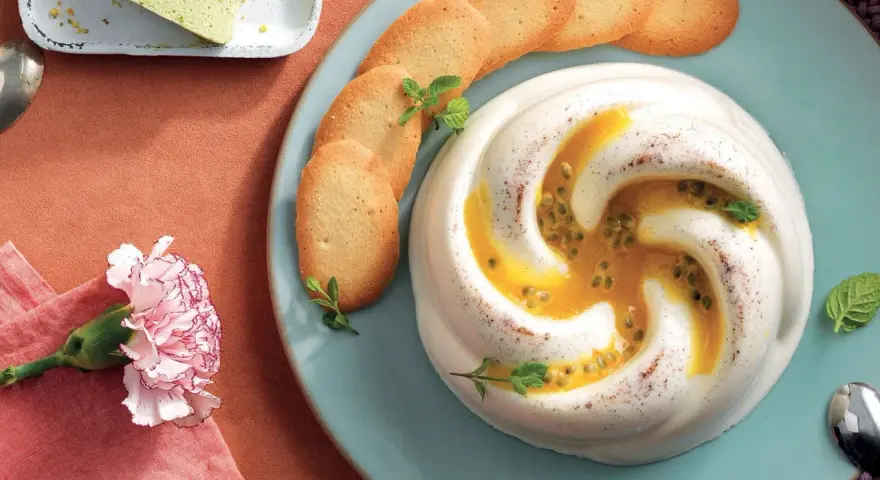 Dolce cremoso con cuore di frutto della passione, guarnito con biscotti e menta.