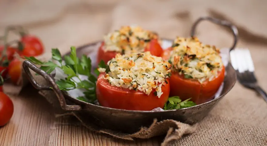 Pomodori ripieni di riso freddi, un piatto estivo gustoso e leggero, serviti in un vassoio rustico con prezzemolo fresco.