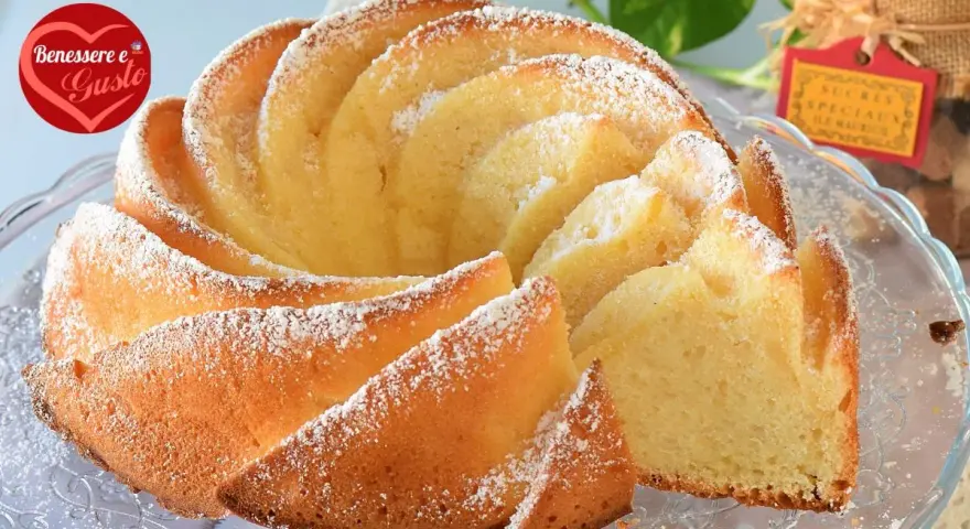 Un soffice ciambellone allo yogurt greco, spolverato di zucchero a velo, pronto per essere gustato.