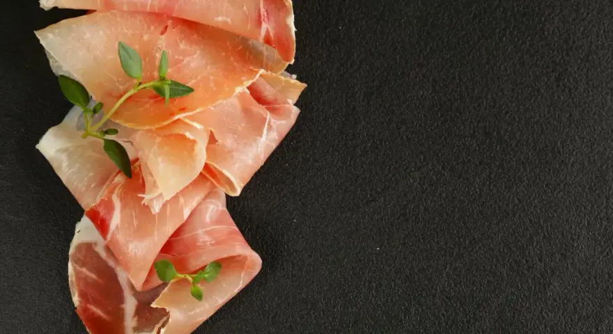 Fettine di prosciutto crudo e speck, con rametti di timo, per mostrare la differenza tra speck e prosciutto crudo.
