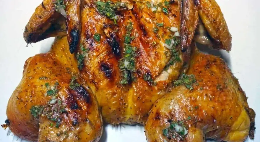 Un succulento pollo alla brace, dorato e profumato, condito con erbe aromatiche e aglio.