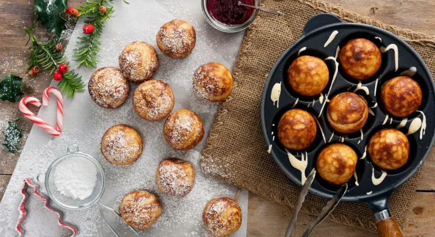 Frittelle dolci in padella, spolverate di zucchero a velo, pronte per essere gustate con marmellata.