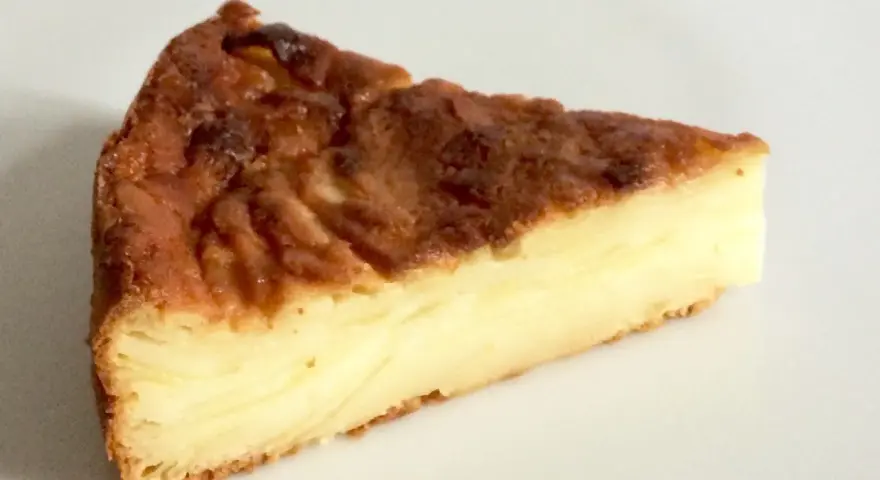 Una fetta di torta di mele fondente, con strati dorati e un ripieno cremoso.