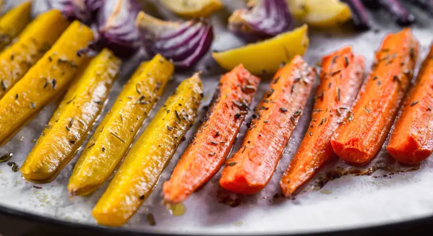 Carote, cipolle rosse e patate dorate, un tripudio di verdure al forno, condite con erbe aromatiche e olio.
